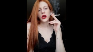 A Girl with Long Red Hair in a Black Dress and Red Lipstick Smokes a Cigarette with a Brown Filter